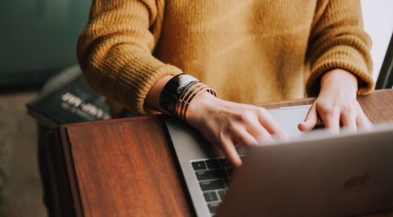 a woman is typing on her laptop computer