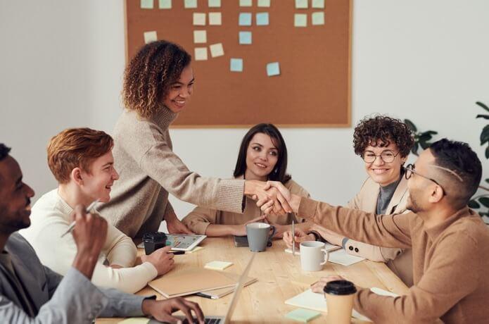 a group of people sitting around a table shaking hands