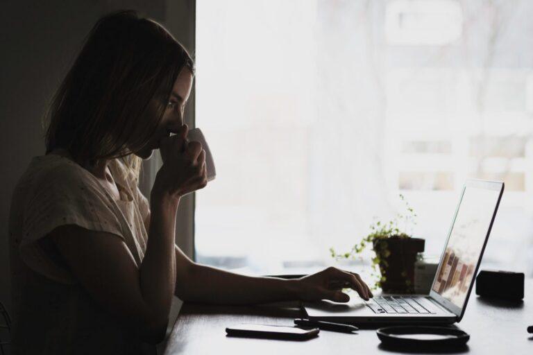 a woman sitting at a table using a laptop computer