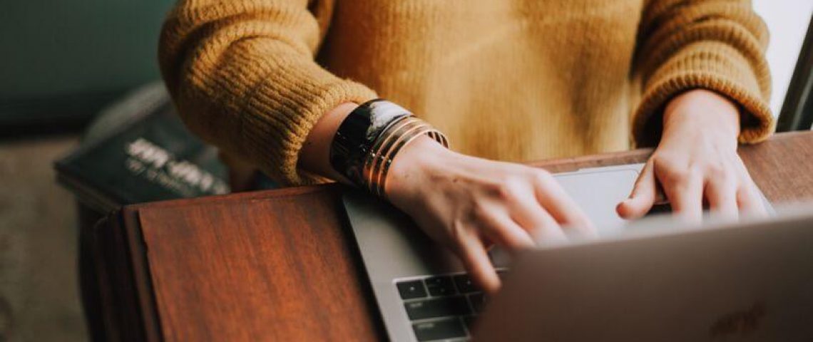 a woman is typing on her laptop computer