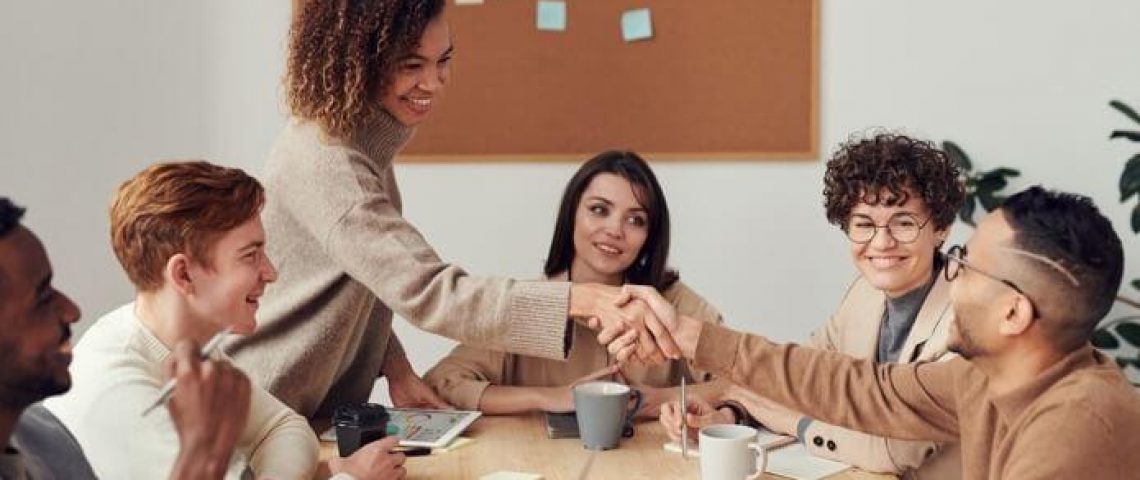 a group of people sitting around a table shaking hands