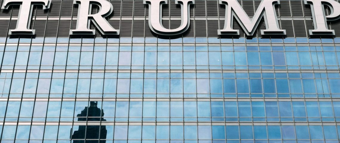 man in black jacket standing in front of glass building