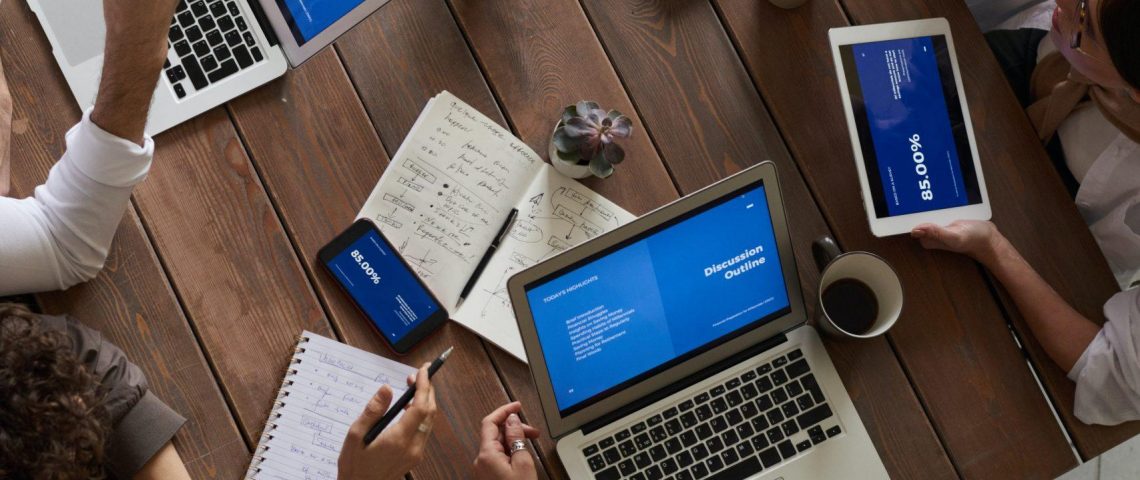 a group of people sitting around a table working on laptops