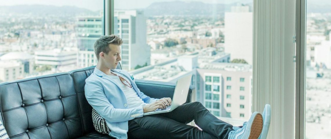 man sitting on sofa while using laptop