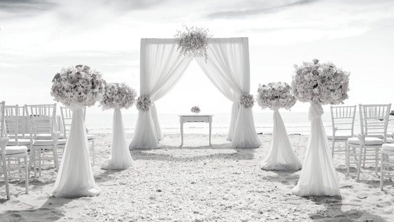 an outdoor ceremony setup with white drapes and flowers