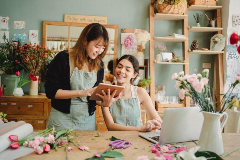 two women sitting at a table looking at a laptop